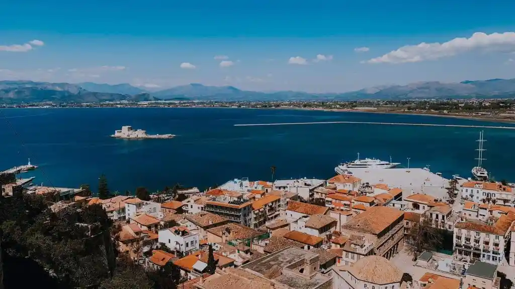Panoramic drone shot of Nafplio Greece showing the traditional old town red roofs and Bourtzi fortress